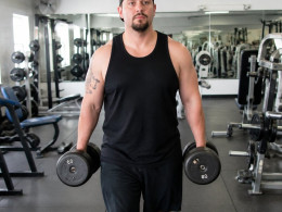 Man carrying heavy dumbbells through a budget gym early in the morning