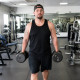 Man carrying heavy dumbbells through a budget gym early in the morning
