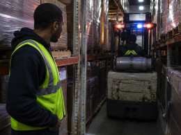 Narrow warehouse aisle with forklift barely fitting between tall racking at night