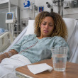 Patient lying in hospital bed with medical monitors and a rideshare receipt on the bedside table.