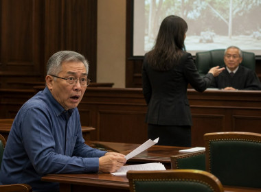 Older East Asian man in courtroom looking shocked as video is played by opposing lawyer.