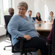 Woman sitting in an office conference room as a smart chair adjusts her posture during a rollout demonstration.