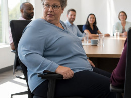 Woman sitting in an office conference room as a smart chair adjusts her posture during a rollout demonstration.