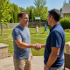 Homeowner shaking hands with contractor in backyard with pool area marked out