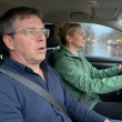 Man with slurred speech sitting in car passenger seat, woman driving through rainstorm.