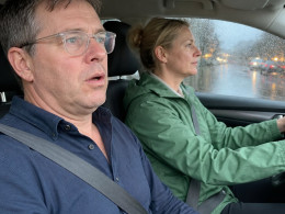Man with slurred speech sitting in car passenger seat, woman driving through rainstorm.