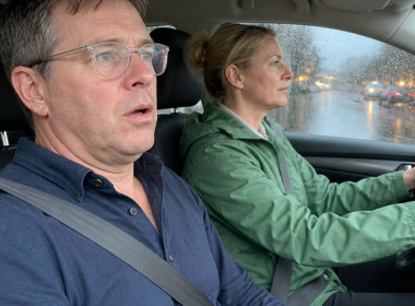 Man with slurred speech sitting in car passenger seat, woman driving through rainstorm.