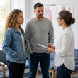 Intake nurse discussing symptoms with young woman and her husband in a cardiology office.