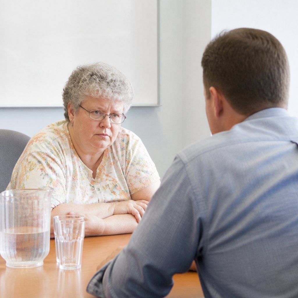 Woman and man discussing a phone recording in a hospital conference room.
